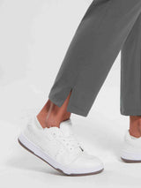 Close-up of dark gray women's jogger pants with a subtle slit at the ankle, paired with white sneakers. #color_Dark Gray