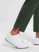 Women's dark green fleece-lined tapered jogger pants with ankle slits and white sneakers. #color_Army Green