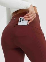 Burgundy 25" fleece-lined yoga leggings with zippered pocket holding smartphone. #color_Wine Red