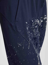 Navy women's jogger pants showing water-repellent fabric with splashing water. #color_Navy Blue