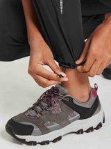 Black hiking pants with adjustable drawstring hem and reflective stripes for outdoor wear. #color_Black