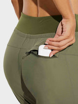 Women's olive green hiking joggers with zippered pocket holding earbuds, high-waisted #color_Light Green