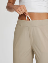 Tan high-rise active pants waist detail: hand pulls white drawstring from pocket opening. #color_Khaki