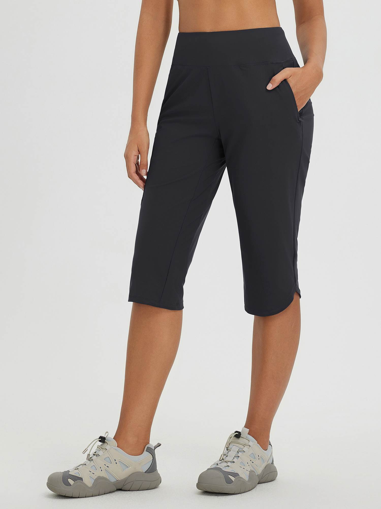 Women's black capri pants for cycling and hiking, featuring pockets and curved hem. #color_Black