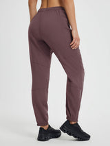 Women's dark plum articulated tapered cycling pants with elastic cuffs and reflective details.