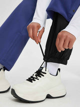 Women's black softshell ski pants with flared leg and adjustable ankle drawstring, white sneakers. #color_Navy Blue