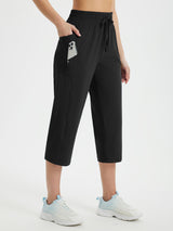 Women's black loose fit athletic capris with drawstring waist and zippered side pocket. #color_Black