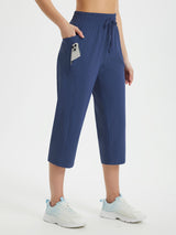 Women's navy blue loose-fit athletic capris with drawstring, side pockets, and zip pocket for phone. #color_Navy Blue