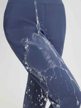 Women's water-resistant thermal fleece pants in blue with water pouring off. #color_Navy Blue