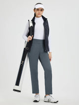 Woman in grey tapered fleece athletic pants, vest, visor, carrying golf bag. #Color_Charcoal Gray