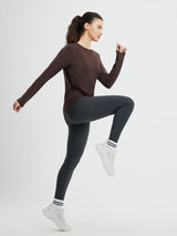 Brown running cross hem long-sleeve t-shirt and dark grey leggings on athletic woman. #color_Dark Brown