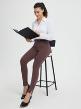 Woman in brown high-waisted tight business yoga pants with split hem, holding folder. #color_Dark Brown