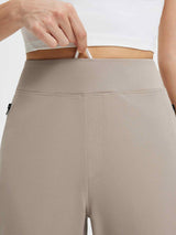 Beige high waisted tapered yoga pants with zippered thigh pocket detail.