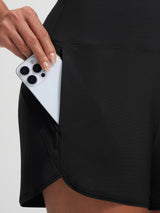 Baleaf black high-rise board shorts with zippered pocket holding smartphone.
