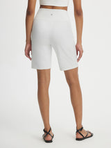 White Baleaf 9" Ultra-Soft V-Waist Bermuda Long Shorts shown from back with black sandals. #color_White