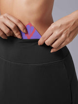 Laureate UPF50+ skort: hands placing card into high-rise black pocket. #color_Black