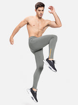 Men's grey fleece-lined water-resistant running tights with orange ankle zip. #color_Gray