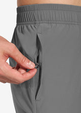 Men's grey running pants: Close-up of hand zipping a deep side pocket. #color_Gray
