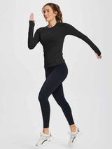 Woman running in black Baleaf compression long-sleeve top with thumbholes. #color_Black