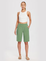 Women's light green 12" cotton Bermuda shorts, wide elastic waist, pockets. Styled with white crop top. #color_Green