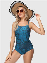 Women's blue one-piece swimsuit with a dark tropical leaf print and adjustable straps. #color_Peacock