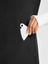 Outdoor sleeveless black fleece thermal dress with pocket holding smartphone.