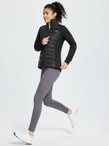 Women's black hybrid quilted jacket with stretch sleeves, stand collar, and grey leggings. #color_Black