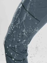 Dark grey fleece mountain pants repelling water splashes, showing water resistance.