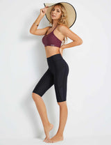 Woman in black Flyleaf UPF50+ high-rise swim shorts and a burgundy sports bra, wearing a straw hat.