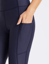 Navy blue Flyleaf UPF50+ high-rise swim shorts with side pockets and a hand reaching into one pocket.