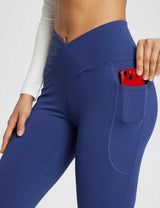 Laureate women's navy blue yoga pants with crossover waist and side pocket holding a red smartphone. #color_Navy Blue