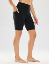 Woman wearing black 8-inch light compression yoga shorts with side pockets.