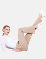 Woman in beige bootcut workleisure pants and white long-sleeve shirt, white sneakers.
