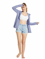 Woman in a light purple UPF 50+ hooded zip-up jacket and distressed denim shorts, shielding her eyes from the sun.