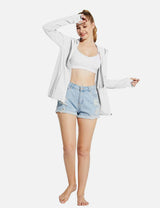 Woman wearing a white UPF 50+ hooded zip-up jacket with thumbholes and light blue distressed denim shorts.