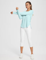 Light blue UPF 50+ long sleeve shirt with thumb loops and white cropped pants worn by a woman stretching. #color_Spa Retreat