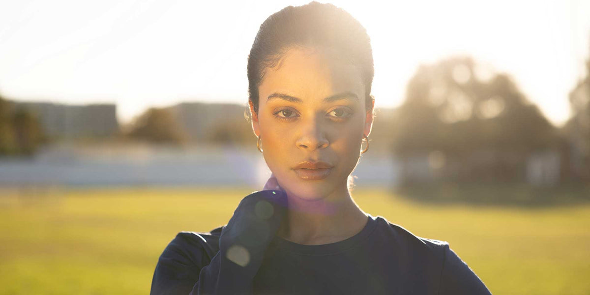 Woman in navy athletic top standing outdoors in golden sunlight