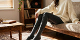 Person sitting on a couch wearing cozy fleece-lined pants and a cream sweater.