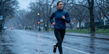 Female runner jogging in heavy rain wearing water resistant running gear on wet street