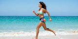 Active woman running on beach wearing floral board shorts women spring break