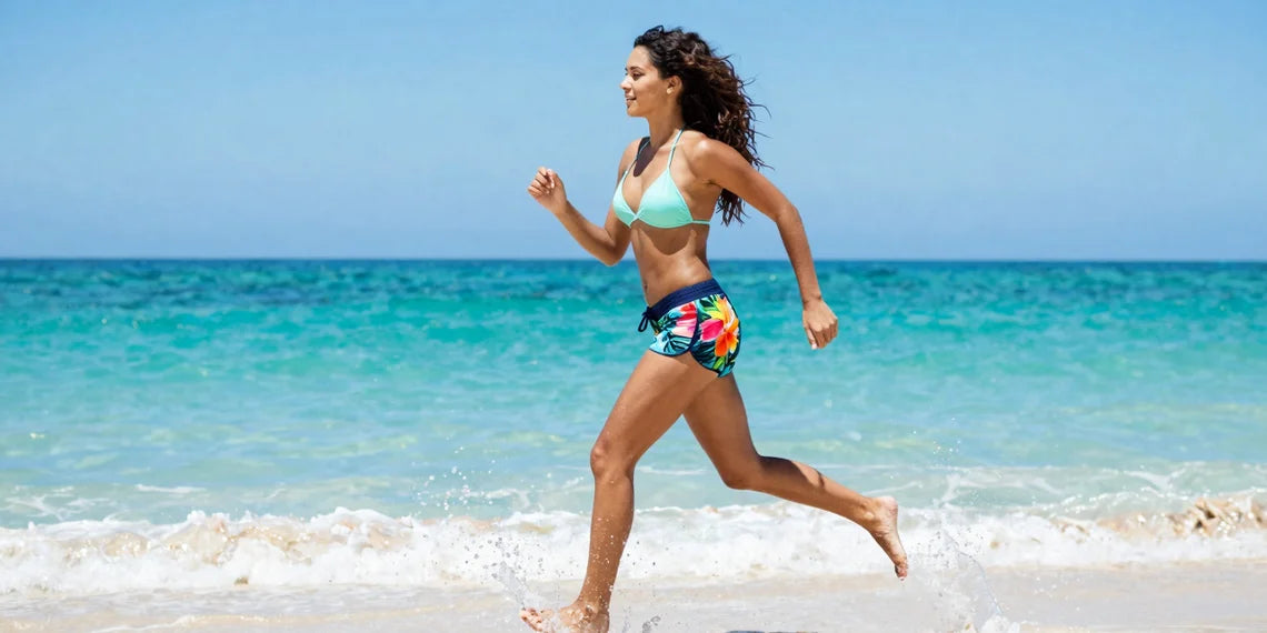 Active woman running on beach wearing floral board shorts women spring break