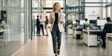Businesswoman walking in modern office wearing Baleaf dark grey straight-leg commuter yoga pants with blazer