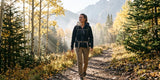 Woman with a backpack walking along a sunlit forest trail