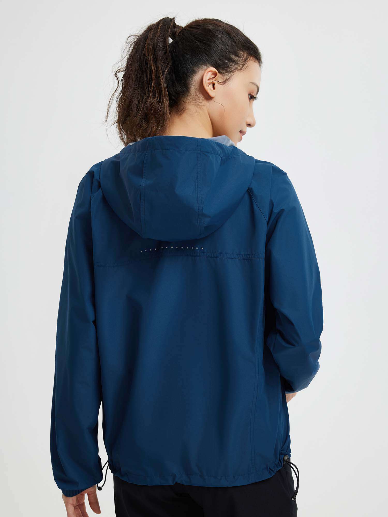 Woman's navy blue packable windbreaker jacket, back view, hood, reflective dots. #color_Navy Blue