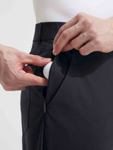 Close-up of black Baleaf golf pants, hand placing golf ball into zippered side pocket. #color_Black