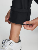 Black women's fleece-lined golf pants shown with hands pulling up hem to reveal thermal lining. #color_Black
