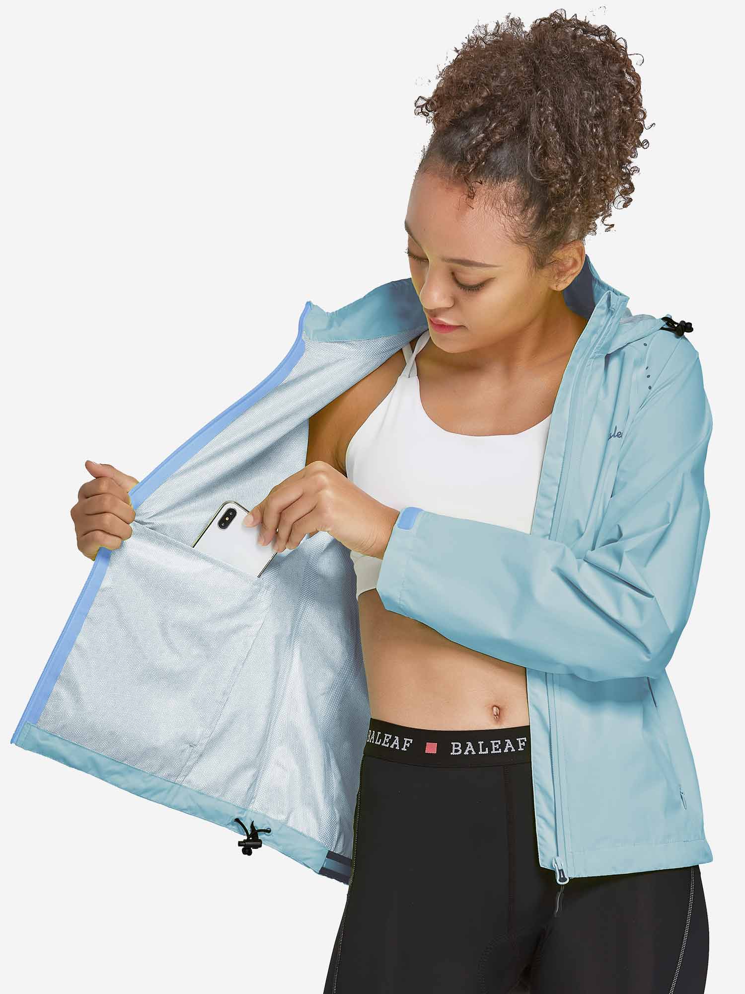 Lightweight light blue women's waterproof cycling rain jacket, woman placing phone in inner pocket. #color_Blue