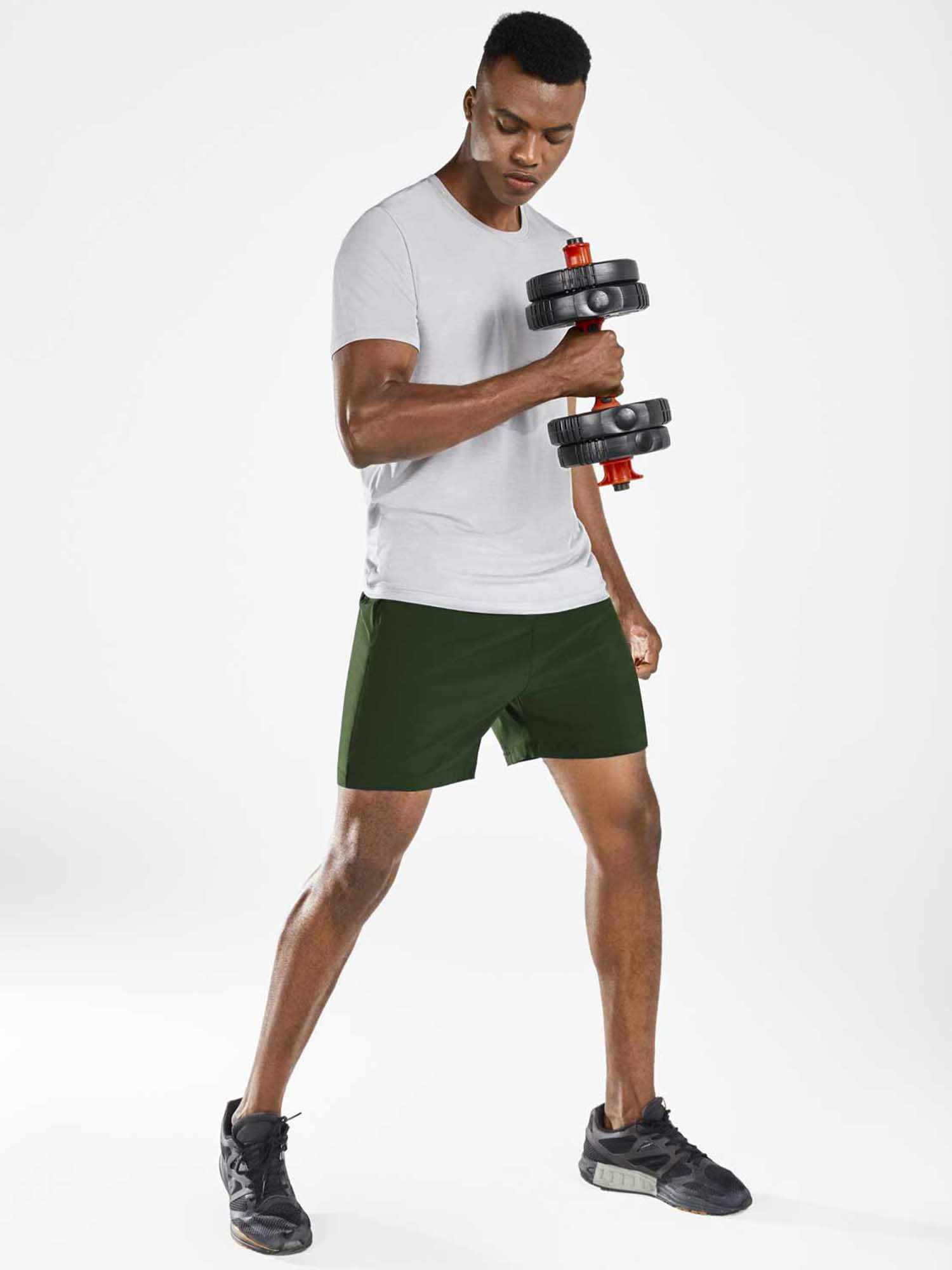 Dark green men's 5" running shorts on athletic model holding dumbbell.