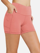 Coral women's high-waisted compression biker shorts with 5" inseam, hand in pocket. #color_Coral Red