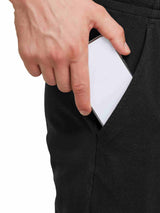 Man placing smartphone into the deep front pocket of black cotton lounge pants. #color_Black